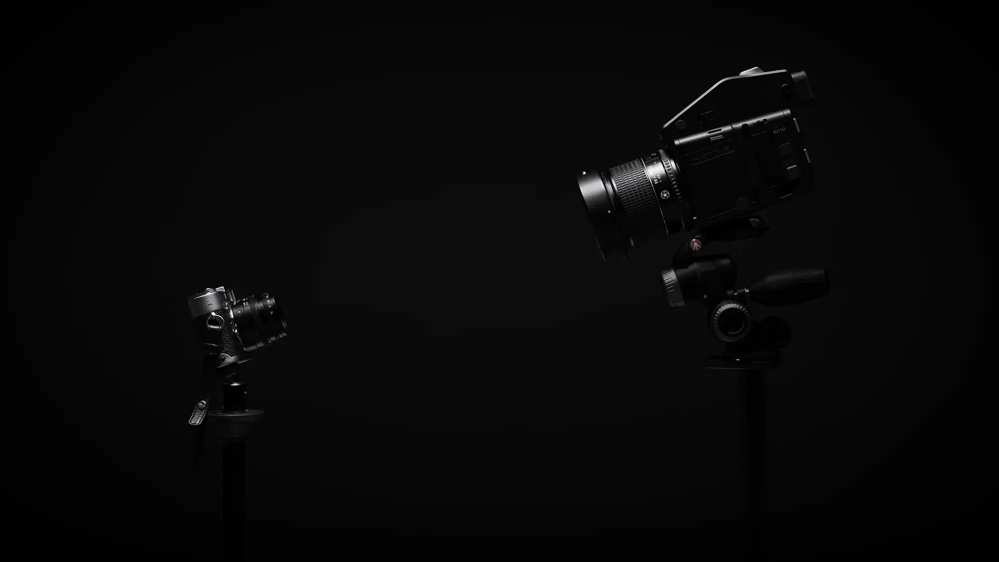 Silhouettes of two cameras against a dark background